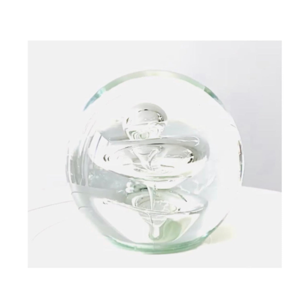 A Murano clear glass paperweight with a few of bubbles inside .