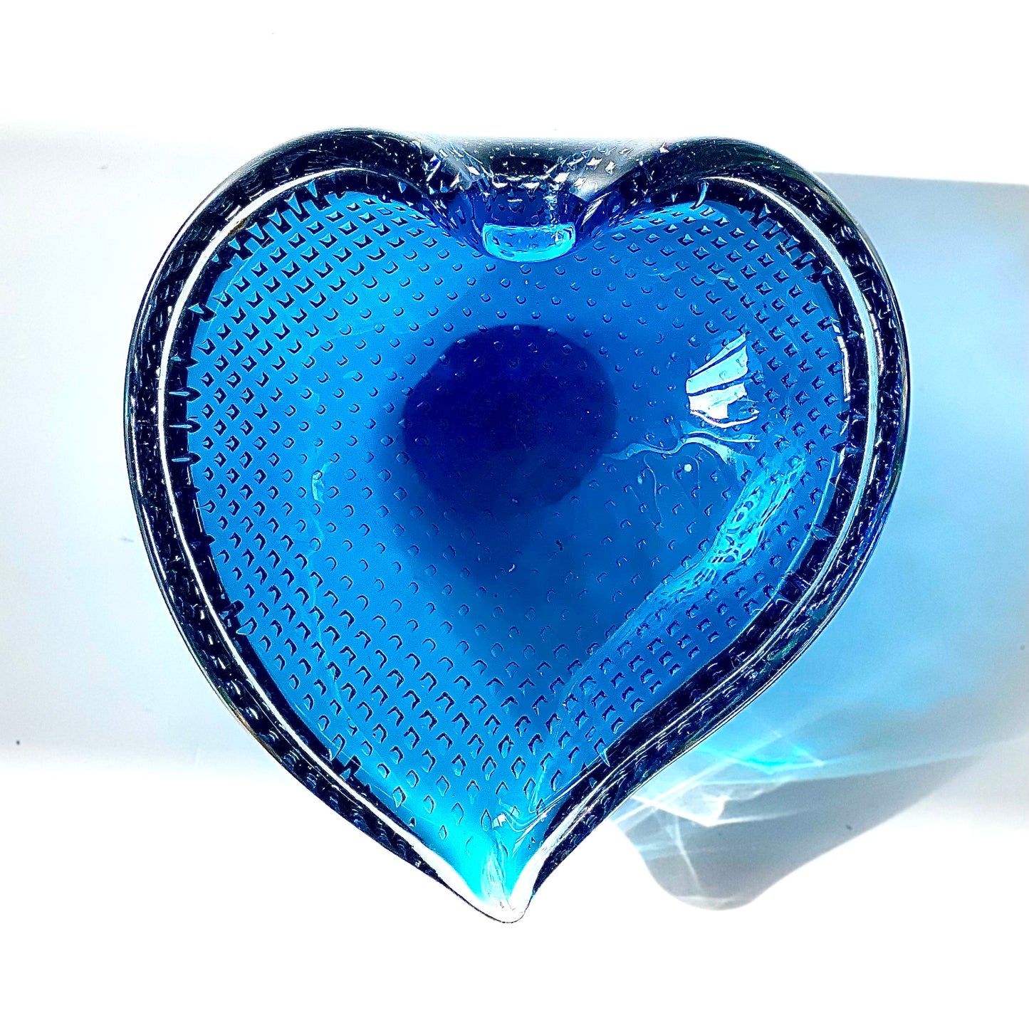 A Murano Bullicante glass bowl in sapphire blue in the shape of a heart.