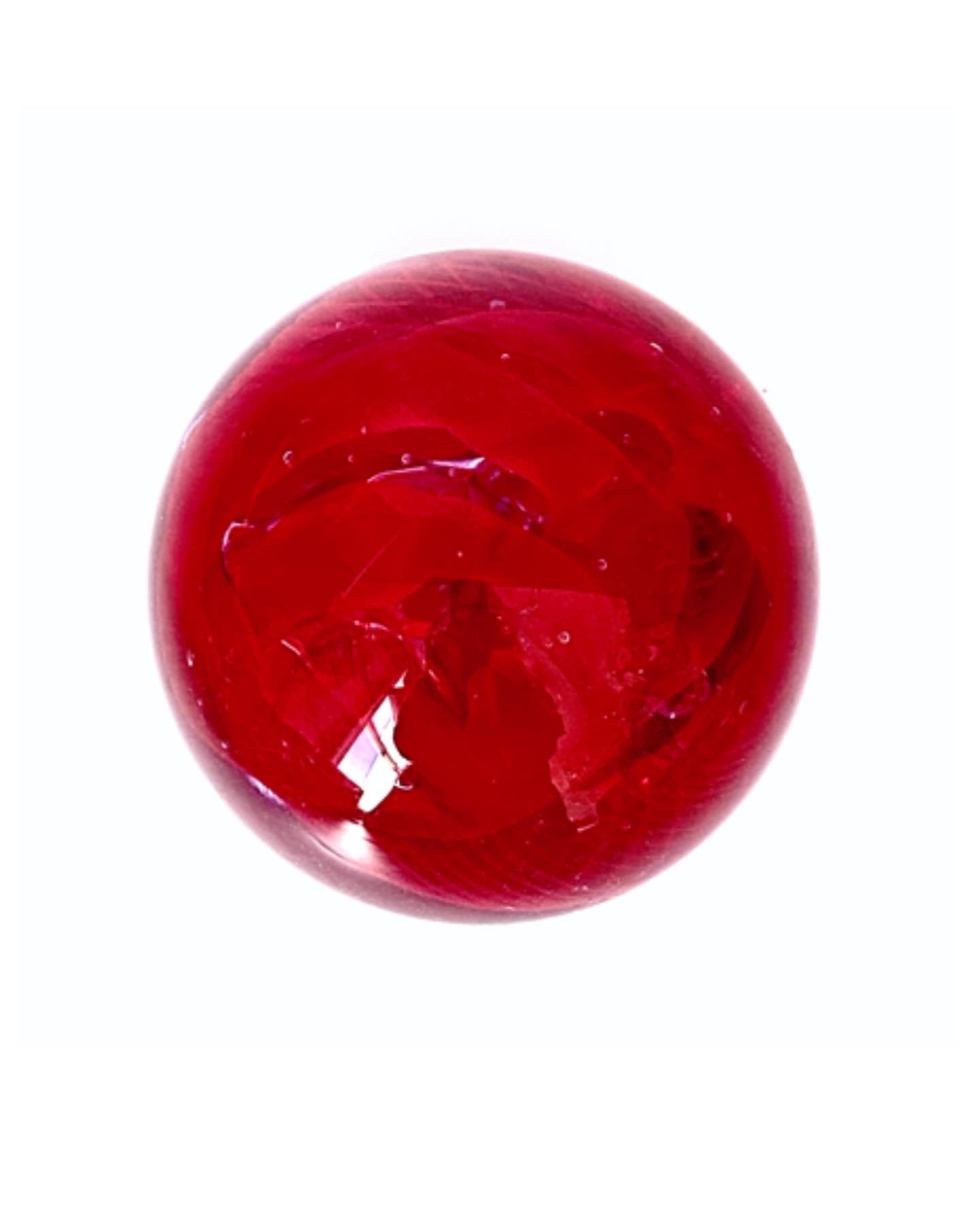 A Caithness lilac with a cherry red swirl inside a glass paperweight.