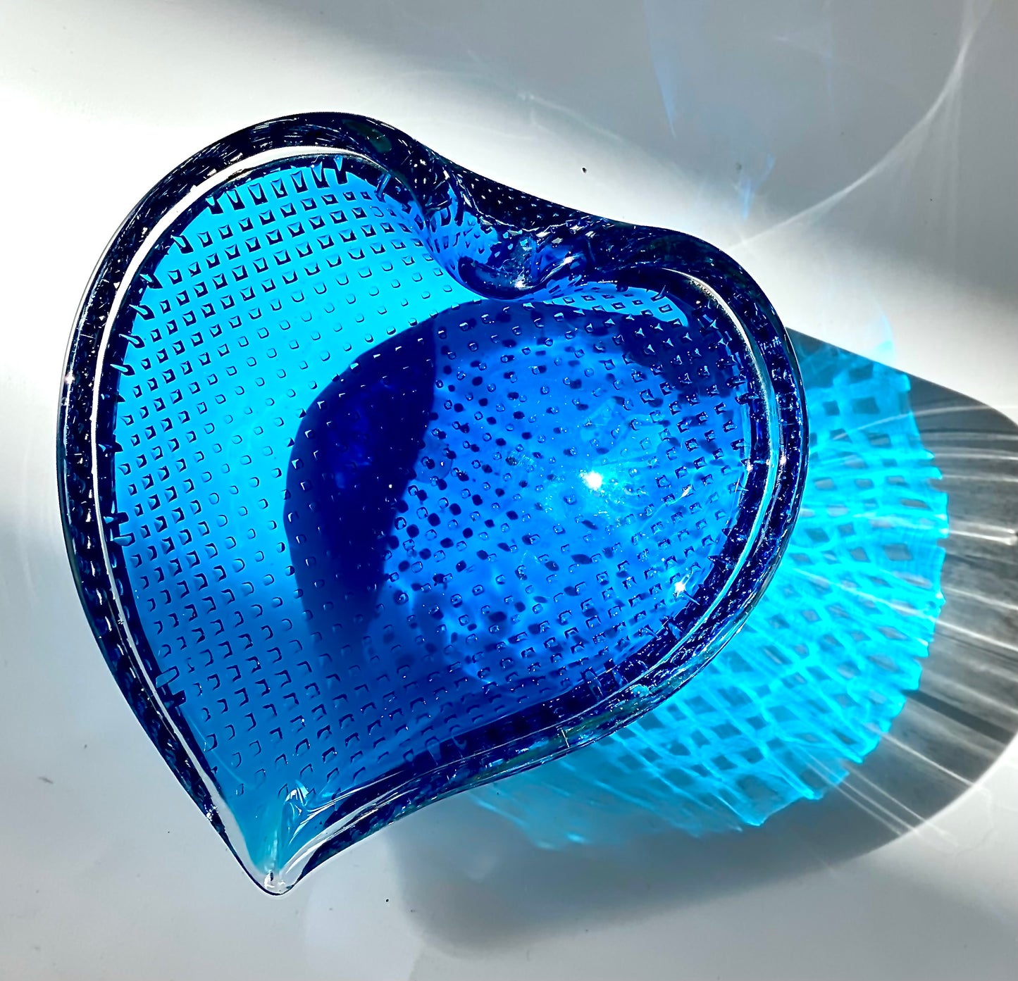 A Murano Bullicante glass bowl in sapphire blue in the shape of a heart.