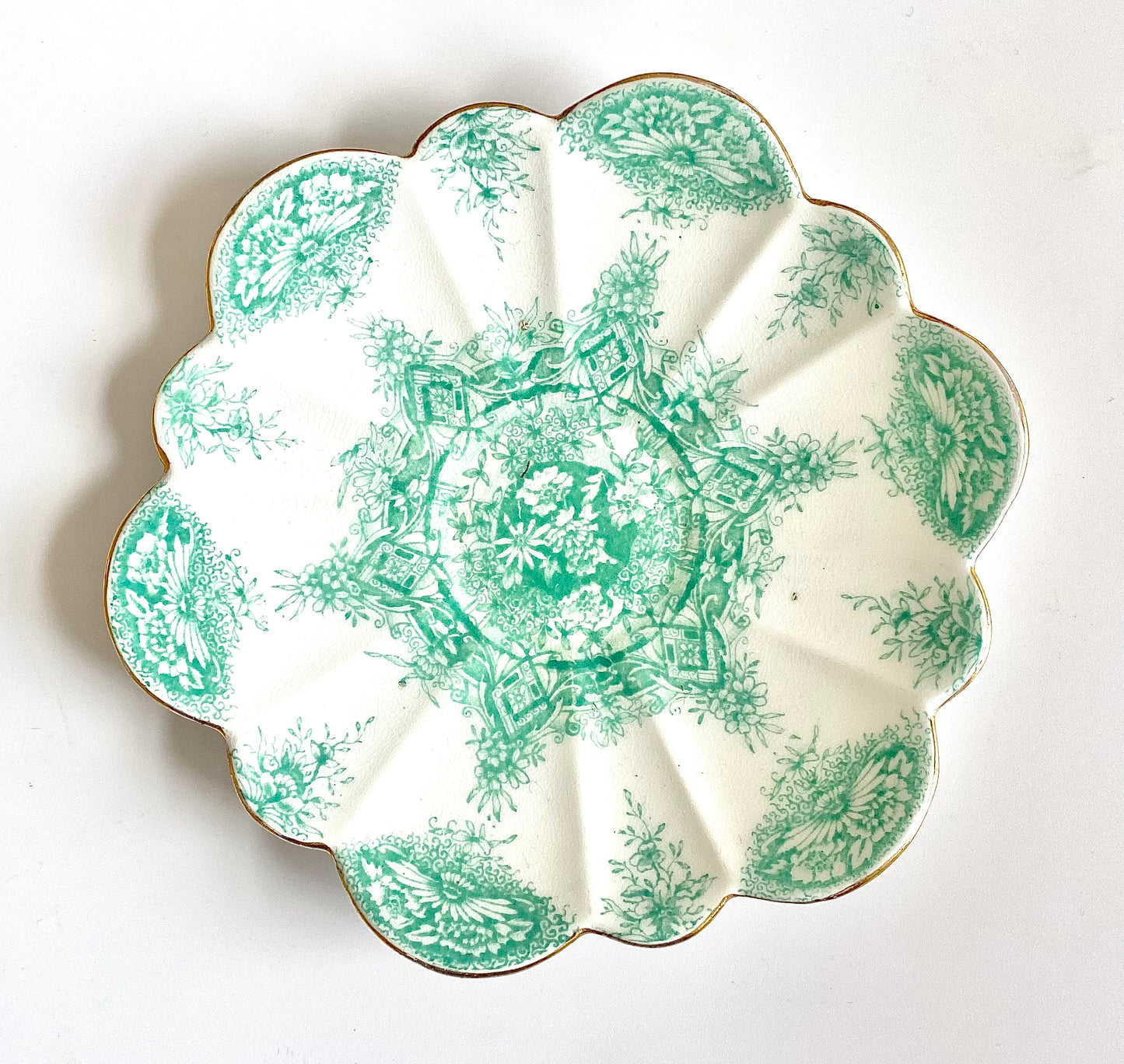 A Chinoiserie set of bone china side plates, a saucer and a cup in a mint green. The plates have scalloped rims with gold lustre edging.