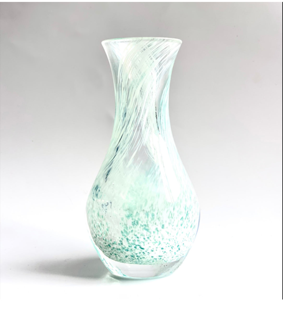 A Caithness glass bud vase in speckled sea green with a soft creamy swirl.