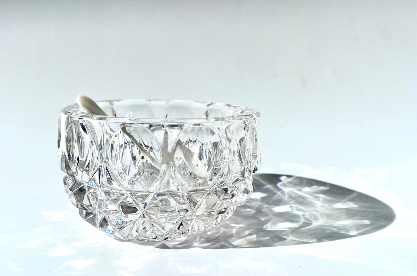 A crystal cut glass salt cellar/mustard pot with a mother of pearl spoon.