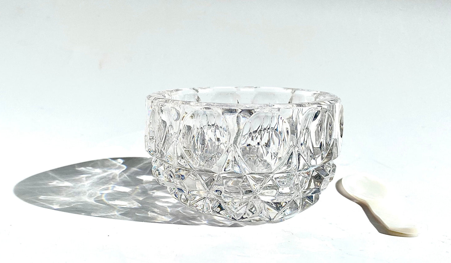 A crystal cut glass salt cellar/mustard pot with a mother of pearl spoon.