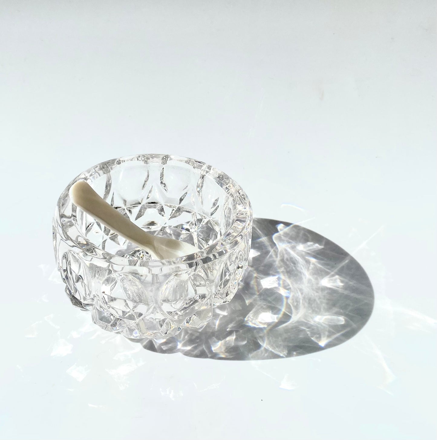 A crystal cut glass salt cellar/mustard pot with a mother of pearl spoon.