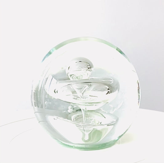 A Murano clear glass paperweight with a few of bubbles inside .