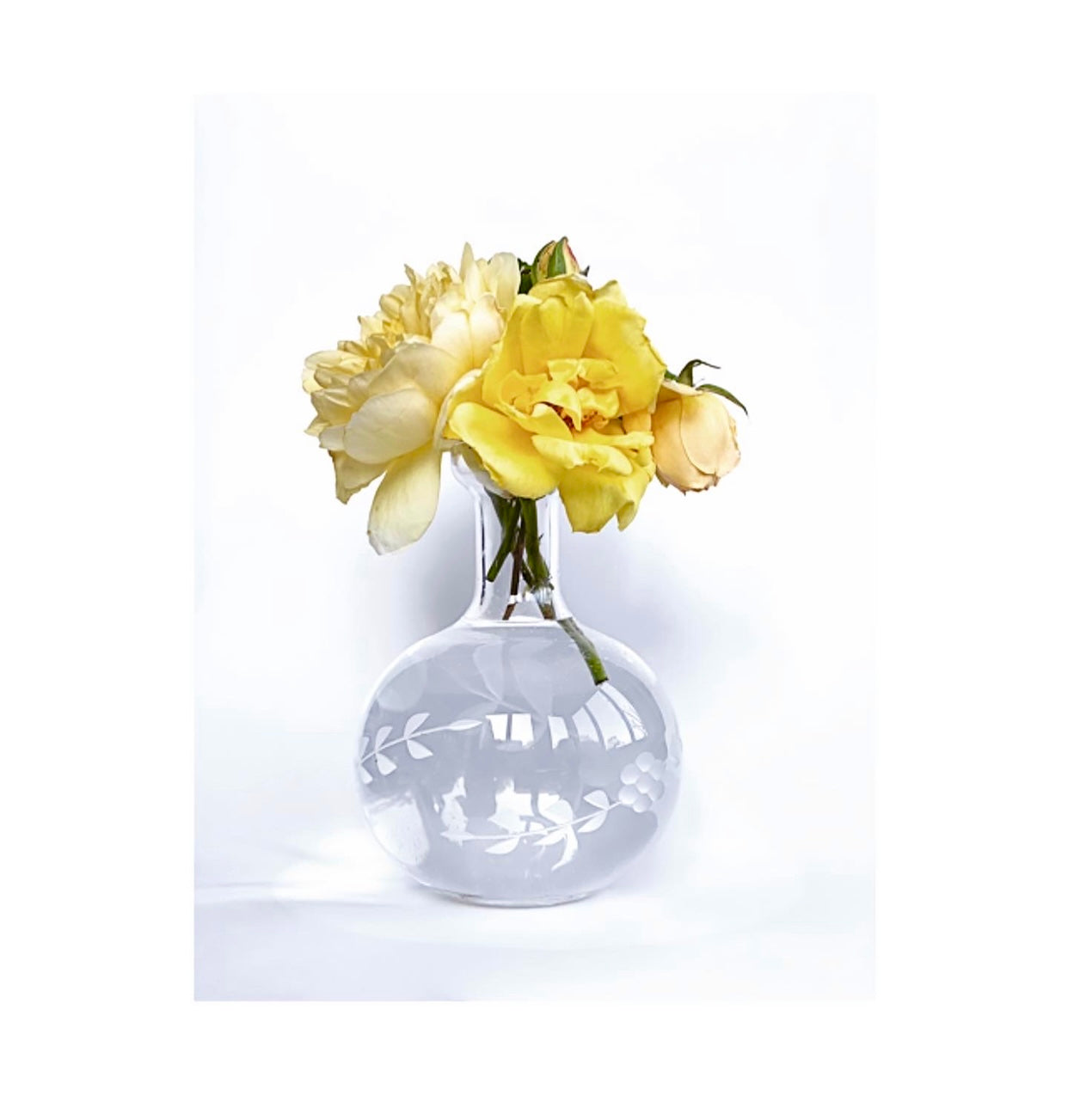 A round bottomed glass vase and jug with leaves etched around the body.