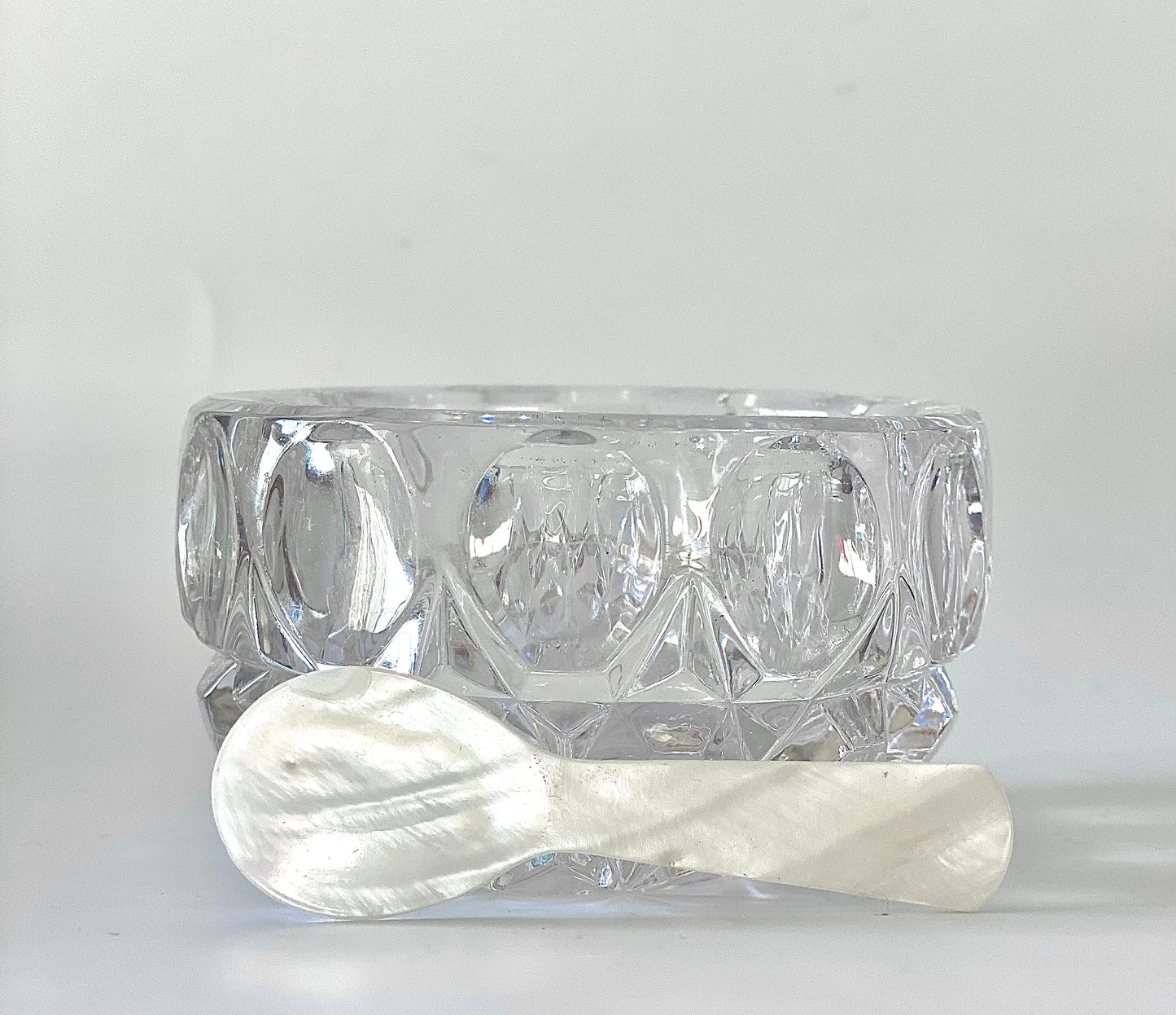 A crystal cut glass salt cellar/mustard pot with a mother of pearl spoon.