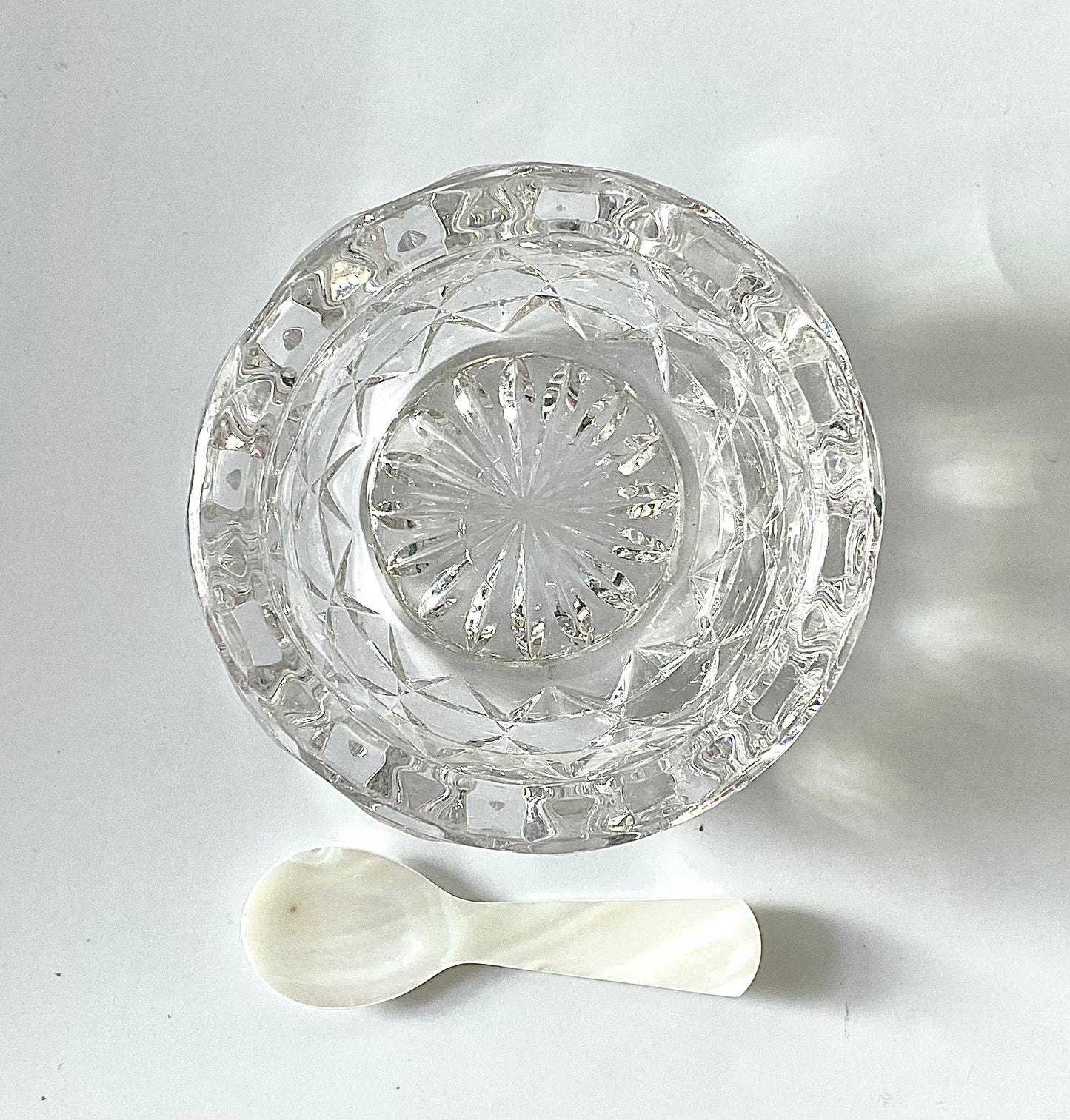 A crystal cut glass salt cellar/mustard pot with a mother of pearl spoon.