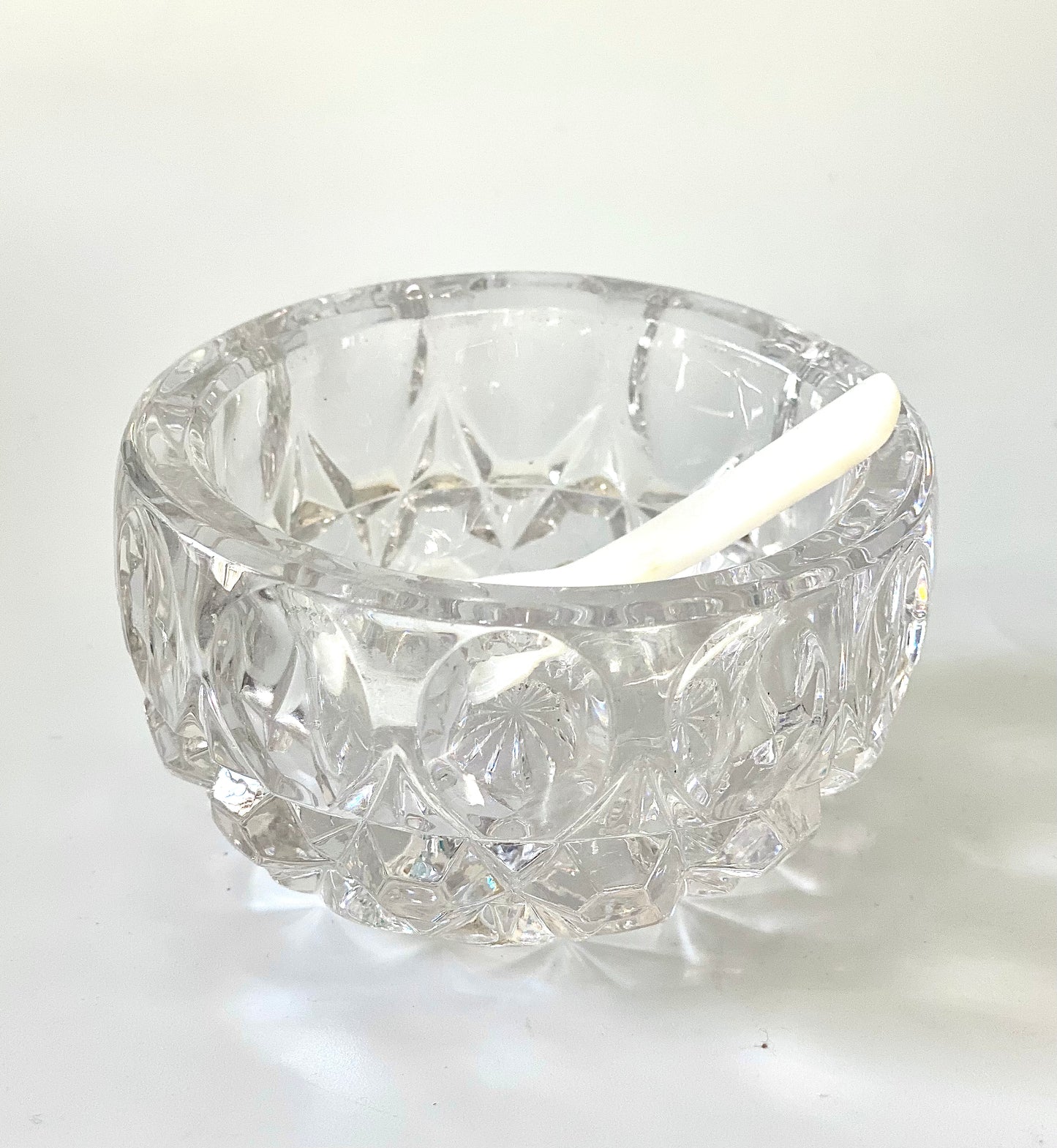 A crystal cut glass salt cellar/mustard pot with a mother of pearl spoon.